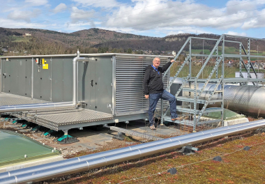 Rainer Gizzi, AKS Air Klima Service AG, vor der sicher montierten Lüftungsanlage der Schweizer Schule 
