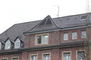  Im Gebäudeteil aus rotem Klinkerstein des Klinikums befindet sich das Ausblasgitter  hinter einem Wetterschutzgitter im Dach. 